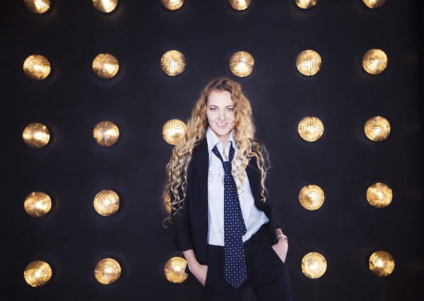 Blond happy woman wearing classical suit over golden shining background
