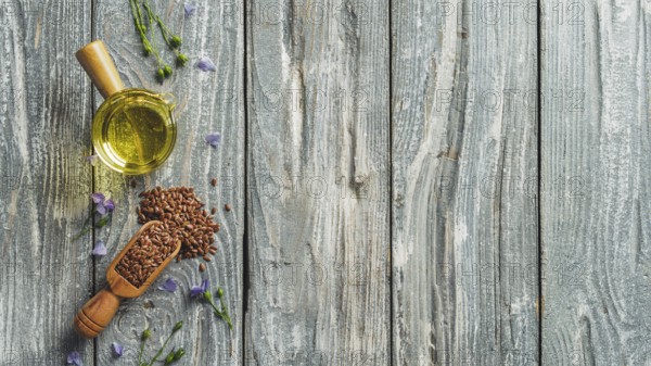 Flax seeds and flax oil. Brown linen seeds and flaxseed oil on old gray wooden background. Copy space. Top view or flat lay