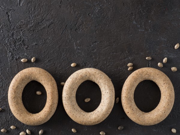 Ring-shaped cracknel with whole grain hemp seed flour and hemp seeds on black background. ring-shaped cracknel close up. Copy space Top view or flat lay