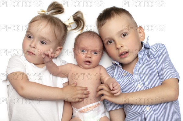 Brother and sister lying together with a newborn baby. Three small children of different ages. Children in the family