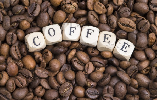 The photo shows roasted coffee beans with wooden letters