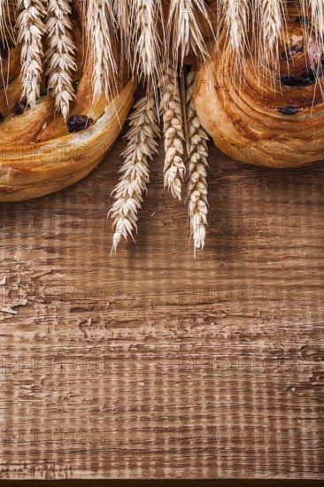 Ripe wheat ears rich raisin baked goods on oaken wooden board food and drink concept
