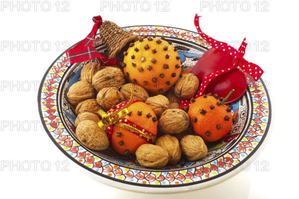 Orange with cloves and walnuts on bowl isolated over white