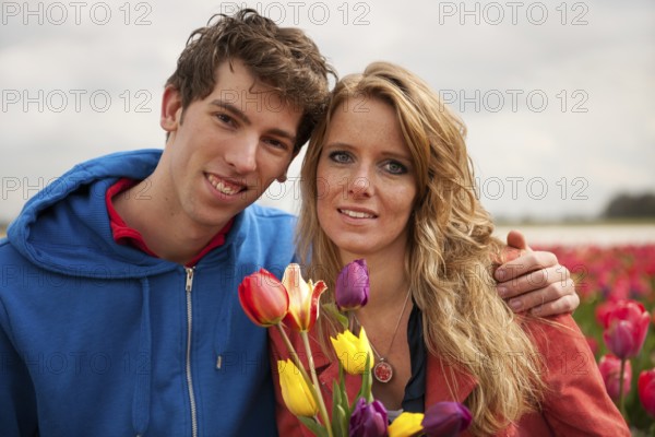Young couple in Dutch flower fields with colorful tulips