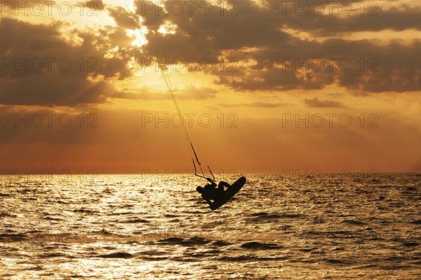 Kite surfer jumping from the water at sunset ocean