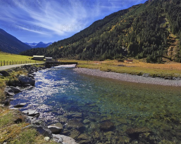 Austrian Alps. Starting famous Krimml waterfalls. Crystal clear water sparkles in the midday sun. Through the narrow creek wooden bridge spanned