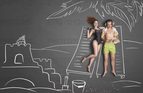 Love story concept of a romantic couple against chalk drawing background. Male lying on sun lounger wearing headphones and reading a book, female taking a picture of a sandcastle
