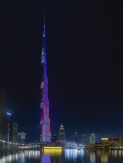 A picture of the iconic Burj Khalifa with its light show, and the surrounding Downtown Dubai buildings and Burj Khalifa Lake, at night