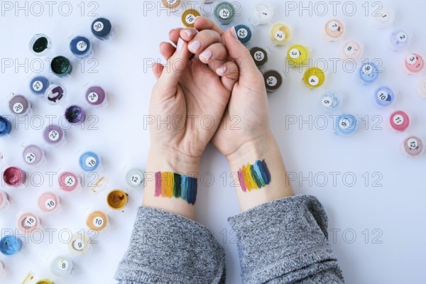Rainbow LGBTQ flag painted on hand. Support for lgbt community. Honour of pride month. Connecting people, touching hands. Multi colored hands art creativity, discrimination