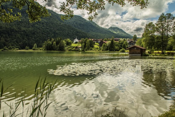 View over the Weissensee lake near Füssen in the Ostallgäu district to Oberkirch with the church of St Nicholas