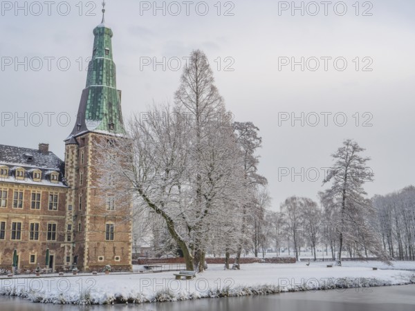 Castle in winter, surrounded by snow-covered trees, with a frozen lake in the foreground, Raesfeld, münsterland, germany