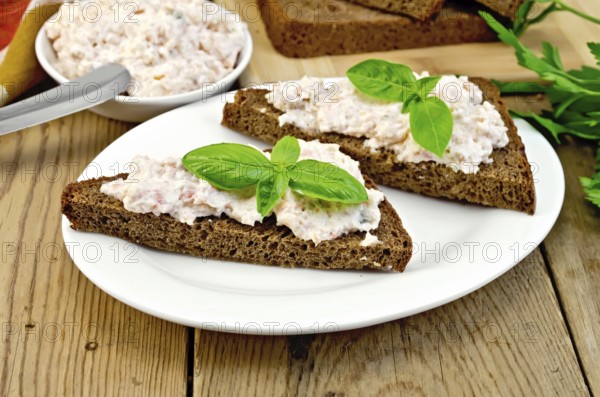Sandwiches on two pieces of rye bread with cream of salmon and mayonnaise, basil, knife, napkin on the wooden boards