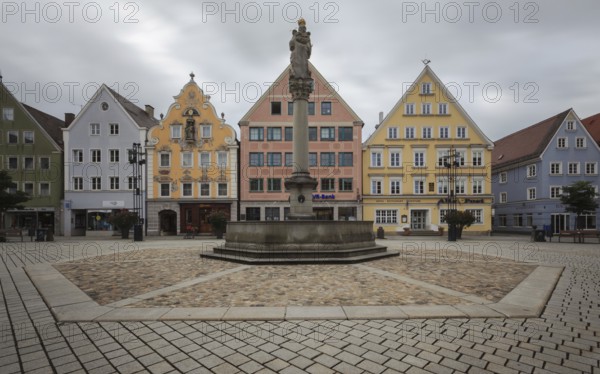 An empty market square with a statue surrounded by pastel-coloured historic buildings, Old Town Mindelheim, Bavaria, Germany, Europe