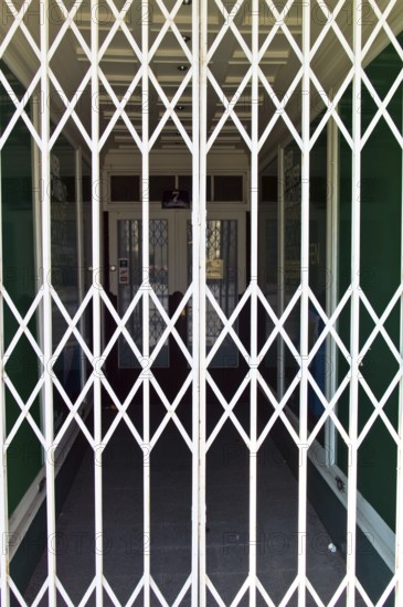 A shop is closed by a scissor gate. Symbol photo for shop opening hours