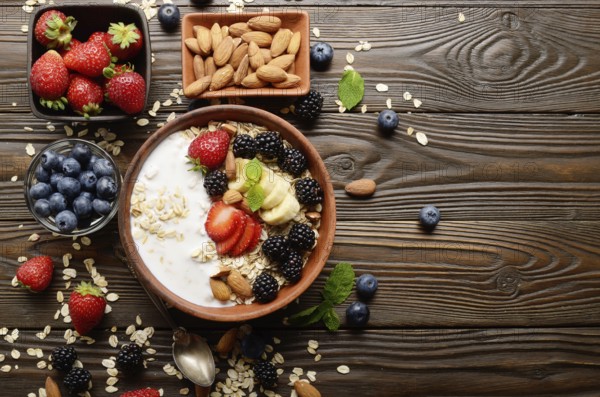 Flat lay top view at Fruit healthy muesli with banana strawberry almonds and blackberry with yogurt in clay dish on wooden kitchen table