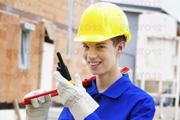 An apprentice / trainee. Construction worker on building site with helmet. Austria