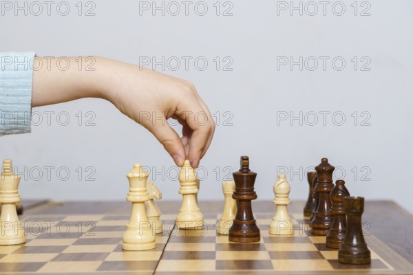 Close-up of a child's hands playing chess with a white background and copy space