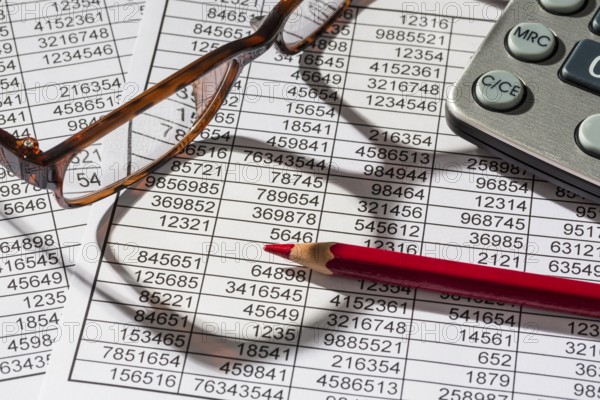 A calculator lies on the figures of a balance sheet and statistics. Symbol photo for turnover, profit and costs