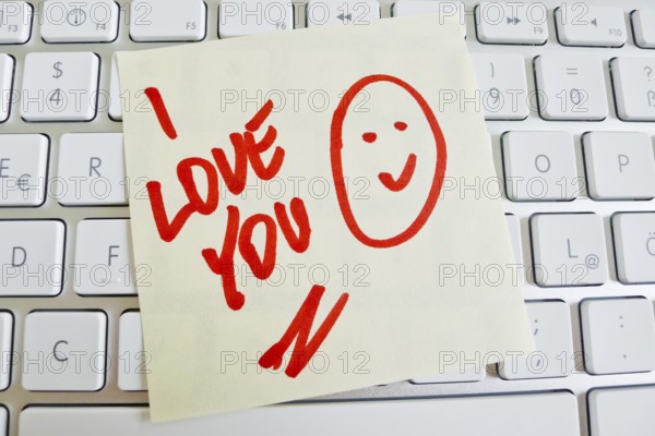 A note lies on the keyboard of a computer as a reminder: I love you Austria