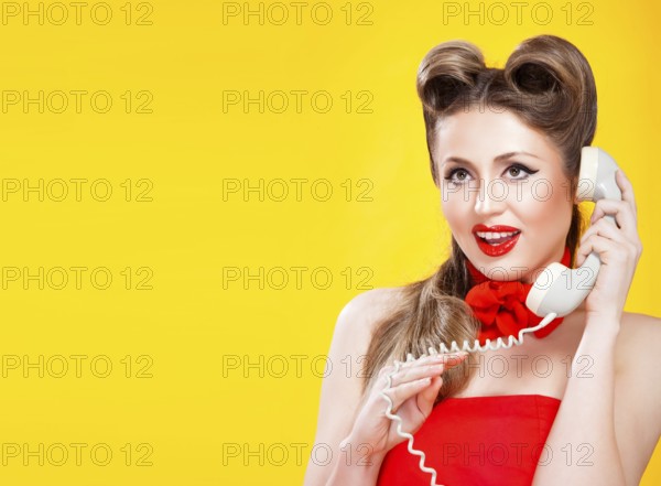 Pin up girl talking on retro phone on yellow background