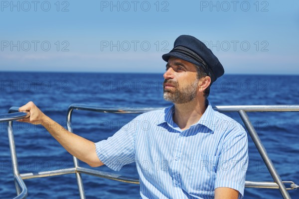 Beard sailor man sailing sea ocean in a boat with captain cap looking horizon