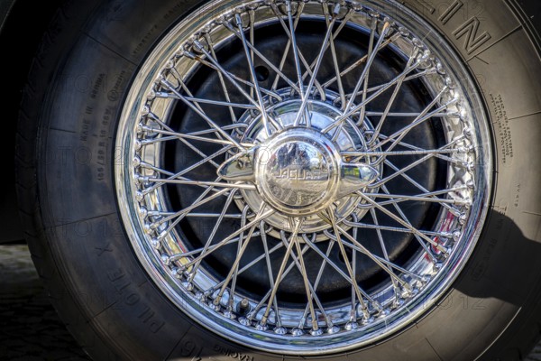 Lisbon, Portugal, Jan 20, 2024: Car design detail of Jaguar chrome wire wheel, stainless steel spokes, polished and chrome-plated with signs of wear-and-tear and bespoke 2-eared wire wheel spinner for splined hub with Jaguar logo. Michelin tyre, Europe