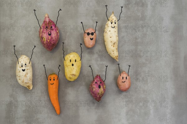 Great concept of healthy eating, vegetables with happy faces with arms up, potato, sweet potato, carrot. Gray background, polished concrete