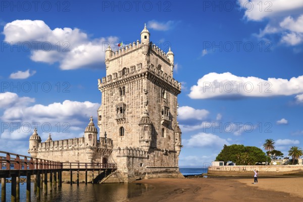 Belem tower and wooden bridge to it, Lisbon, Portugal at blue summer day sky with clouds. Medieval fort on Tagus river in late Gothic or Manueline style, UNESCO world heritage site, Age of Discoveries, tourist attraction, Portuguese seafaring history