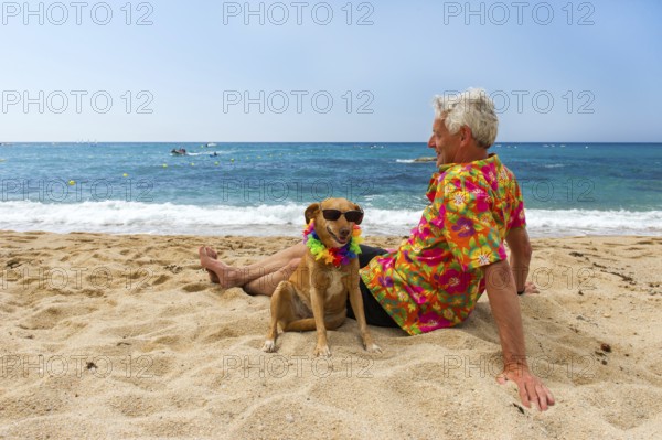 Relaxing elderly man with dog laying at the beach