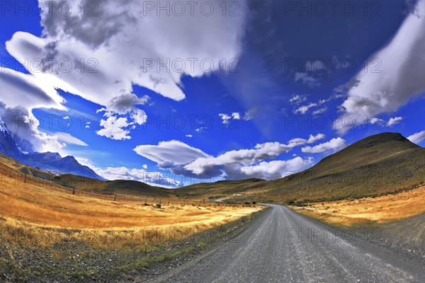 Patagonia. A dirt road in the Chile National Park Torres del Paine. Magic clouds incredible shapes formed by glaciers shining in the sun. Picture taken with a fisheye lens