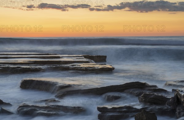 Dramatic beautiful sunset on a rocky coast with waves crashing on the rocks at Akrotiri area in Limassol, Cyprus. Long exposure photography