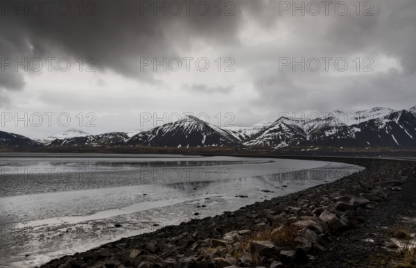 Icelandic dramatic landscape with frozen lake and mountains covered in snow in Iceland