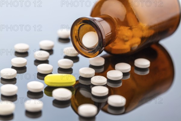 Many tablets with a glass container. Symbolic photo for addiction and costs in medicine and medication. Austria