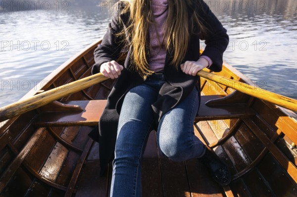 Young woman using paddle on a wooden boat, Lake Bled Slovenia rowing on wooden boats on a sunny day