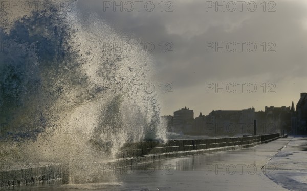 Massive ocean splash against a sea wall on a stormy, overcast day by the coast, Saint-Malo, Ille-et-Vilaine, France, Europe