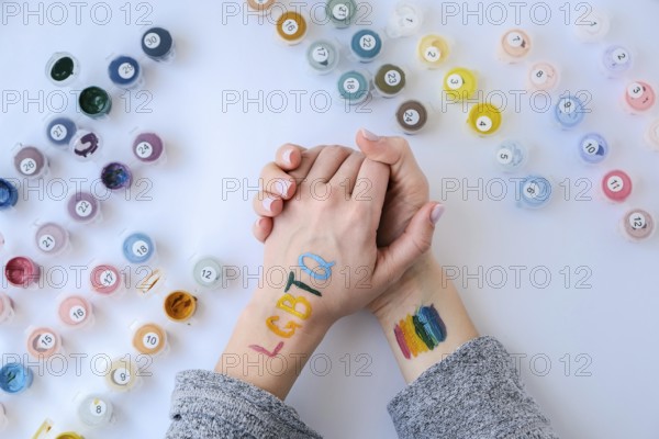 Rainbow LGBTQ flag painted on hand. Support for lgbt community. Honour of pride month. Connecting people, touching hands. Multi colored hands art creativity, discrimination