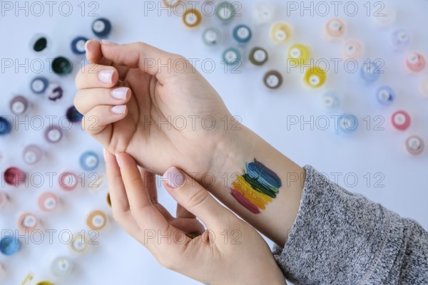 Rainbow LGBTQ flag painted on hand. Support for lgbt community. Honour of pride month. Connecting people, touching hands. Multi colored hands art creativity, discrimination