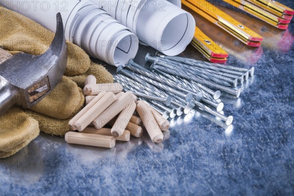 Construction drawings hammer safety gloves wooden meter metal nails and dowels on scratched metallic surface maintenance concept