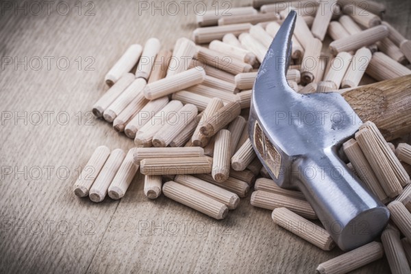 Dowel pins and claw hammer on wooden board construction concept