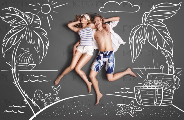 Happy Valentines love story concept of a romantic couple on a desert island, sharing headphones, and listening to the music against chalk drawings background of a sea and a treasure chest