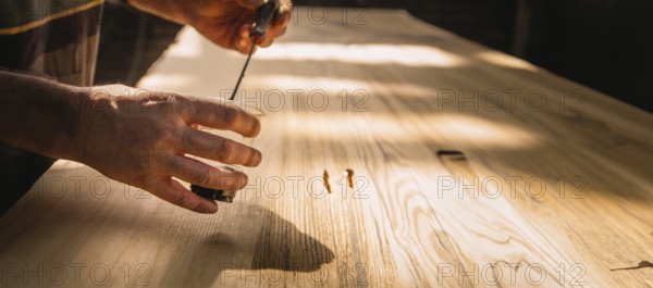 Close-up of hands working on a wooden tabletop, with sunlight creating a serene working environment