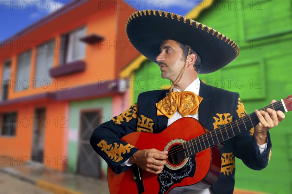 Charro Mariachi singer playing guitar in Mexico houses background