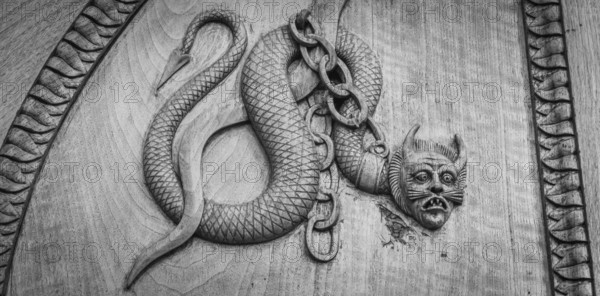 Devil snake symbol. Fantasy magic creature on an old door, 12th Century Abbey, Italy, Europe