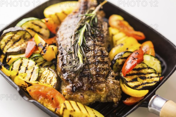 Beef steak with grilled vegetables in skillet