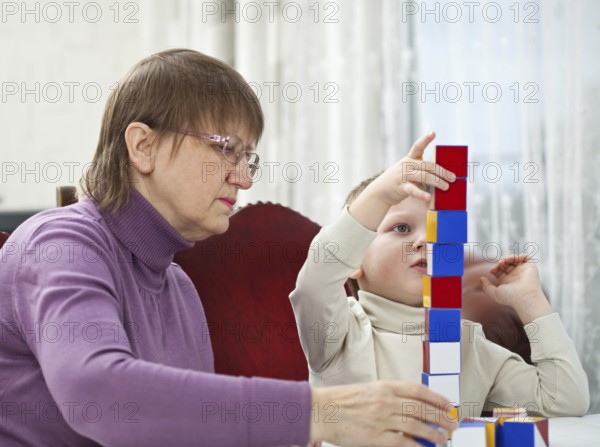Granny is playing blocks with her grandson at home, Belgium, Europe