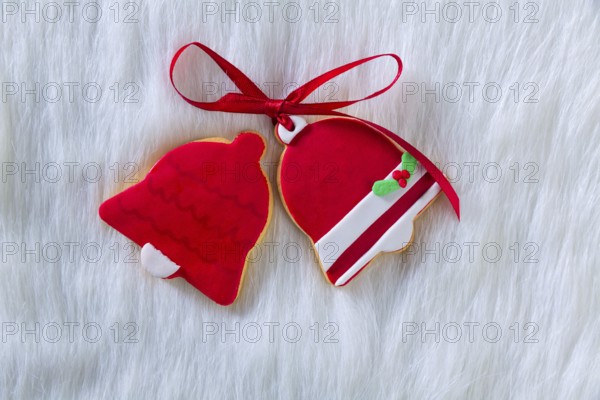 Christmas cookies Xmas red bell shape and ribbon on white fur background