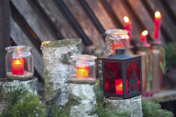 Red candles in glasses and a lantern stand on wood with green branches, borken, münsterland, germany