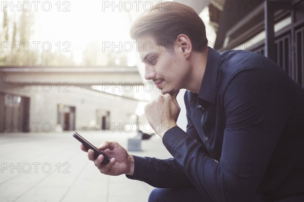 Smiling businessman use a smartphone at street