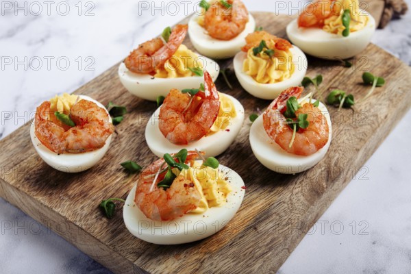 Boiled eggs stuffed with yolk and seasoned with mayonnaise, stuffed eggs with shrimp, on a wooden chopping board, selective focus, close-up, no people