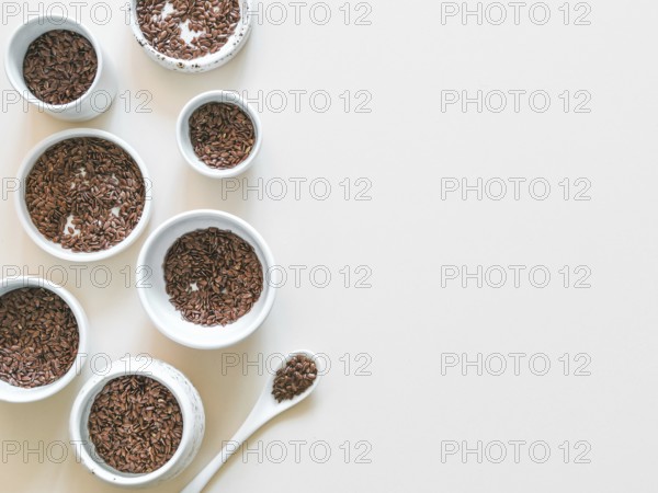 Flax seeds on white or light beige background. Set of small bowls with organic flax seed or linen seed. Flax seeds is rich in omega-3 fatty acid. Copy space. Top view or flat-lay